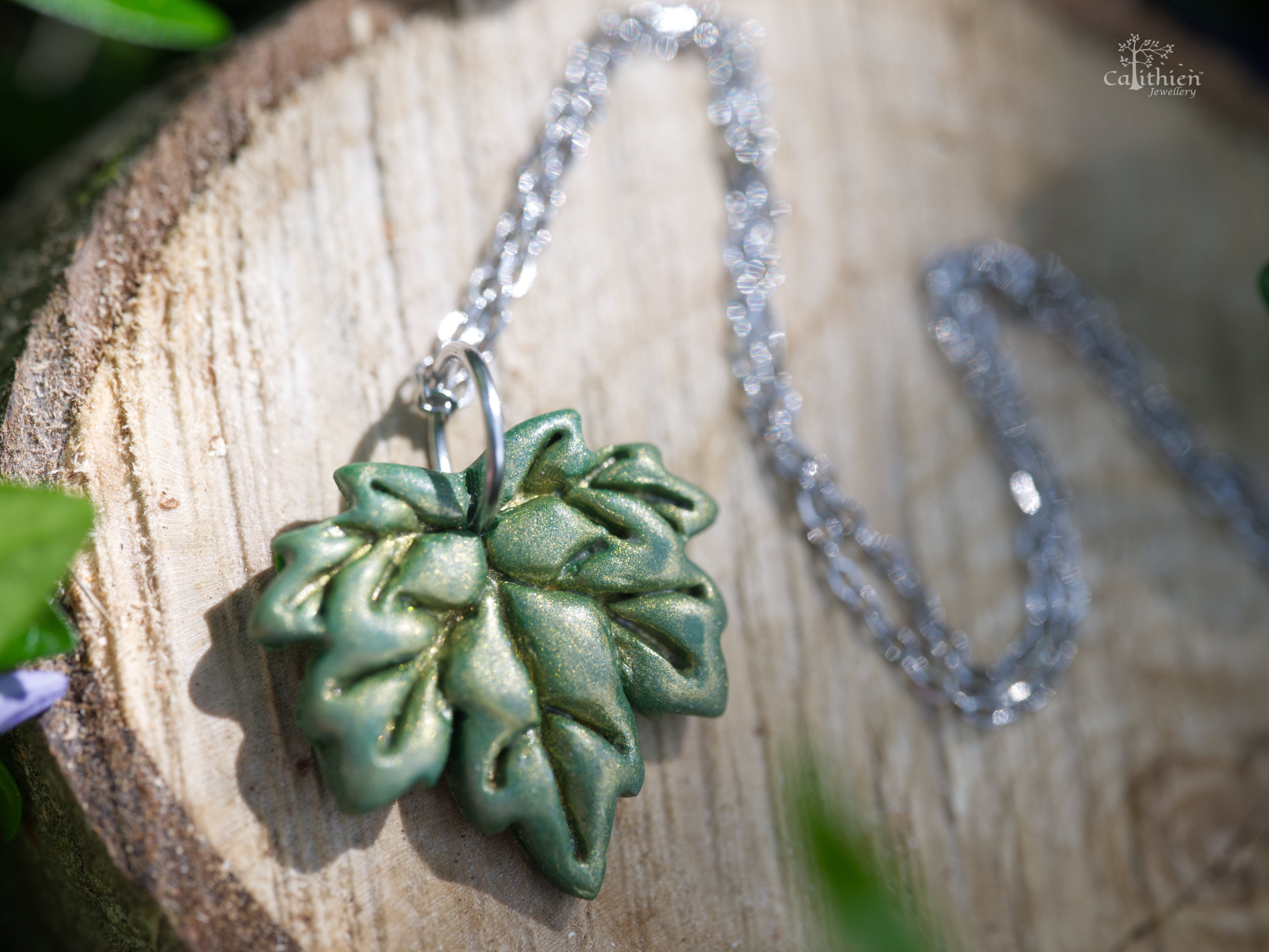 Close-up of green shimmer polymer clay maple leaf pendant showing hand-sculpted vein detail and light-catching shimmer finish