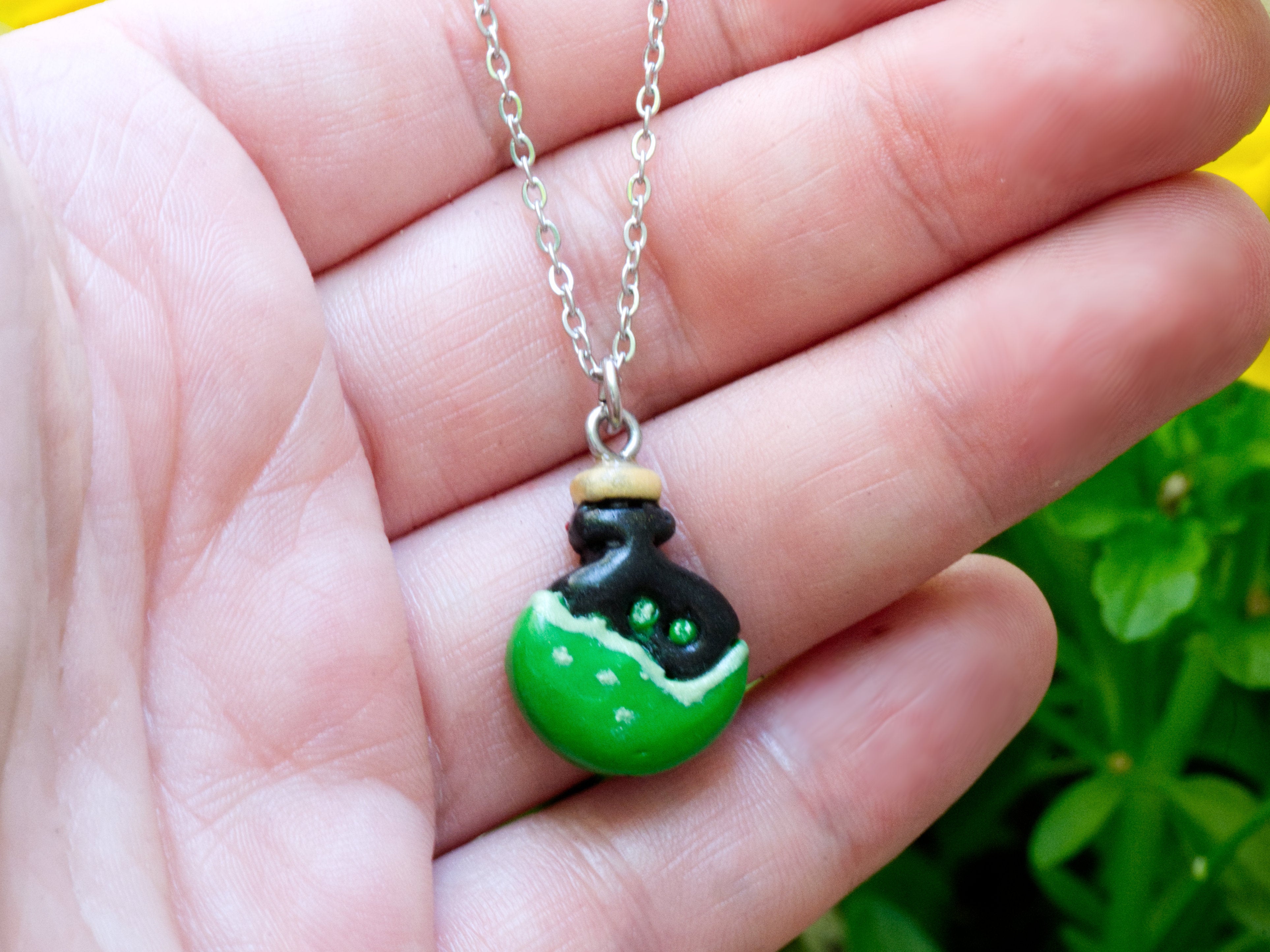 Polymer clay potion bottle necklace pendant on hand to demonstrate size