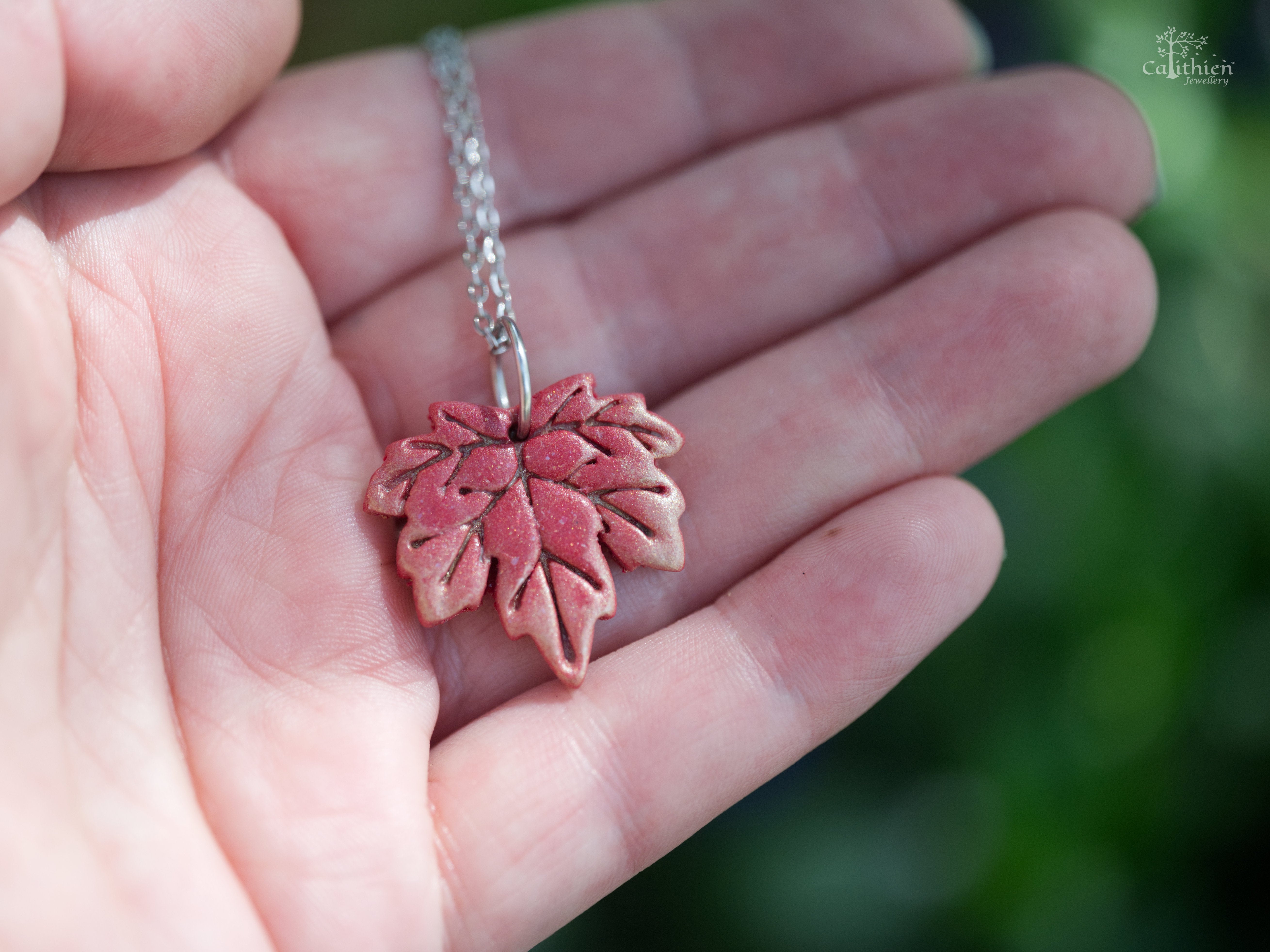 Red maple leaf polymer clay pendant on hand to demonstrate true size
