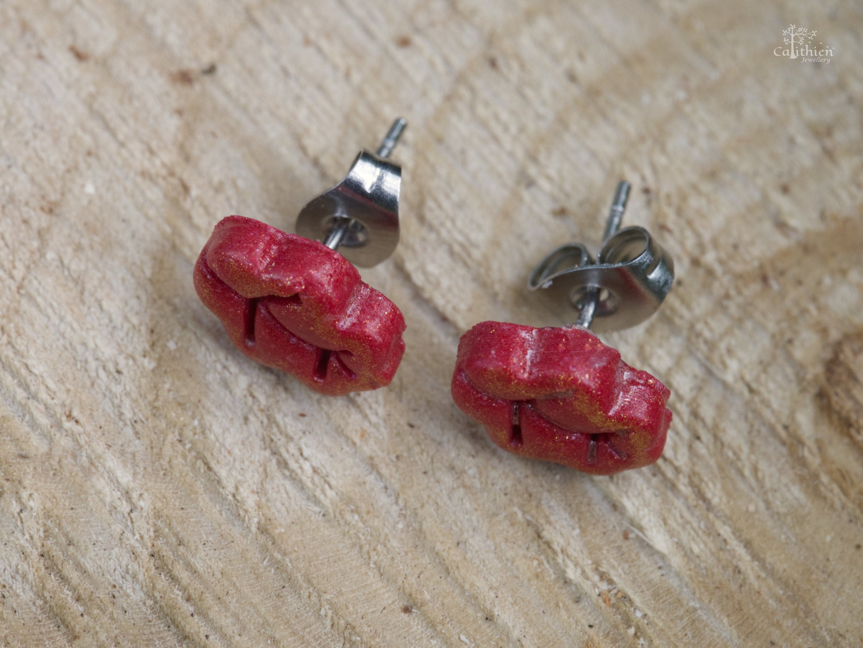 Close-up of red shimmer polymer clay oak leaf stud earring showing vein and lobe detail