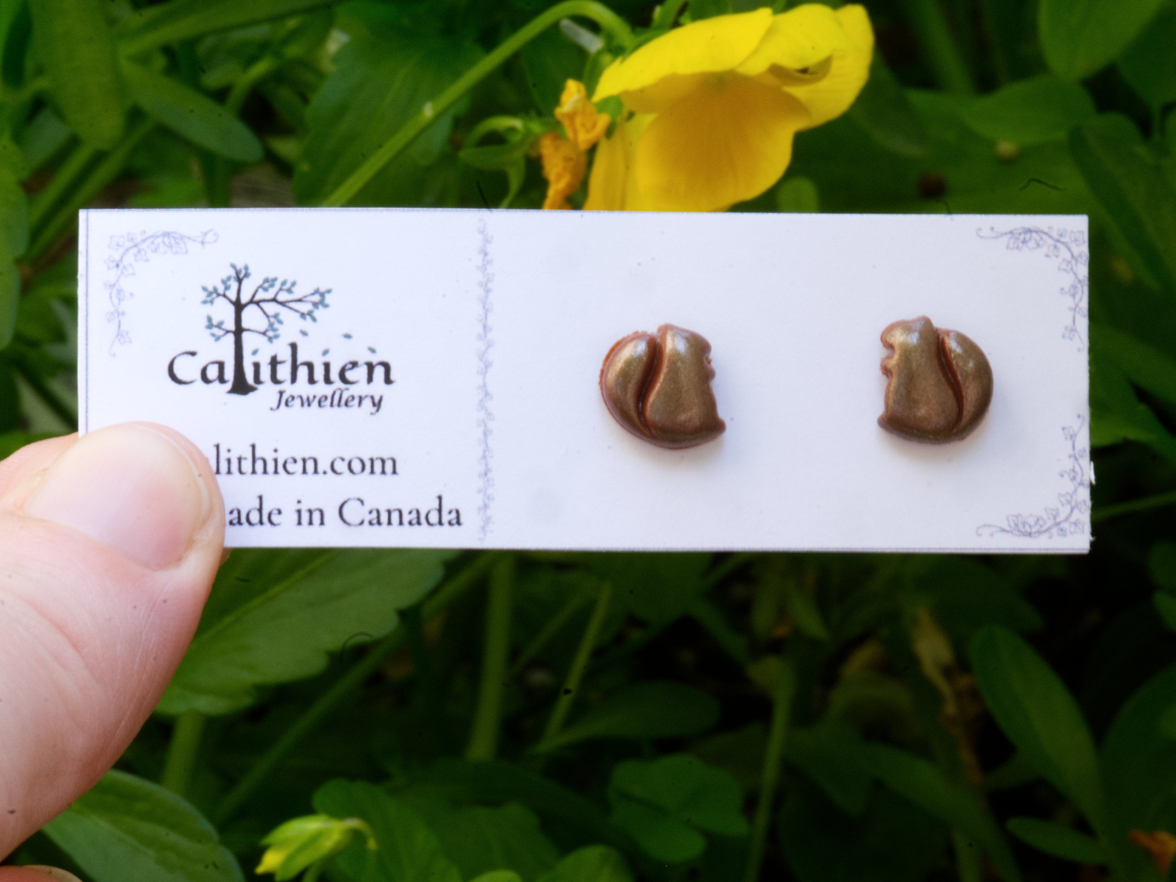 Squirrel stud earrings held in fingers on Calithien Jewellery branded display card reading Handmade in Canada