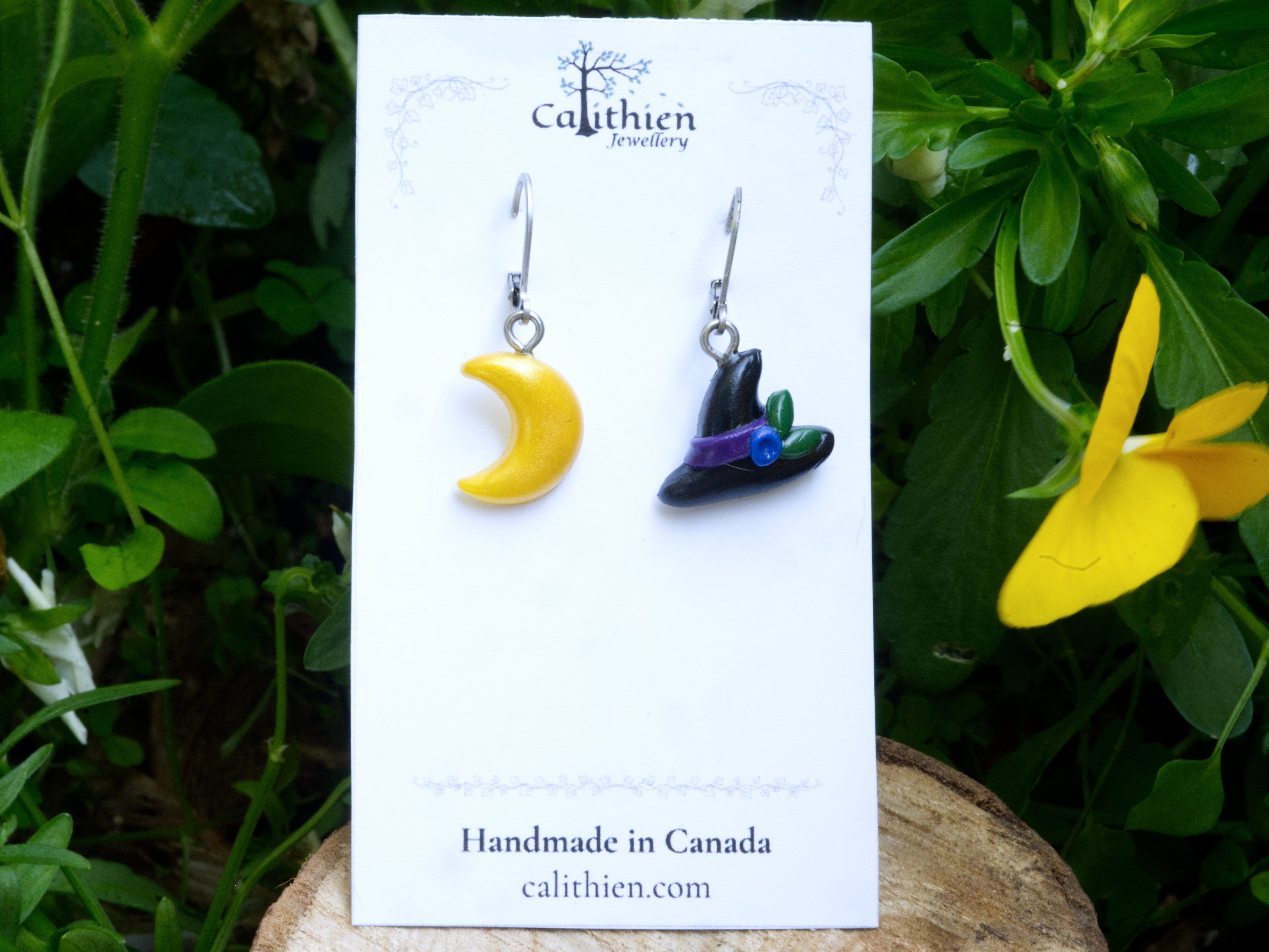 Mismatched witch hat and moon leverback earrings on Calithien Jewellery branded display card reading Handmade in Canada