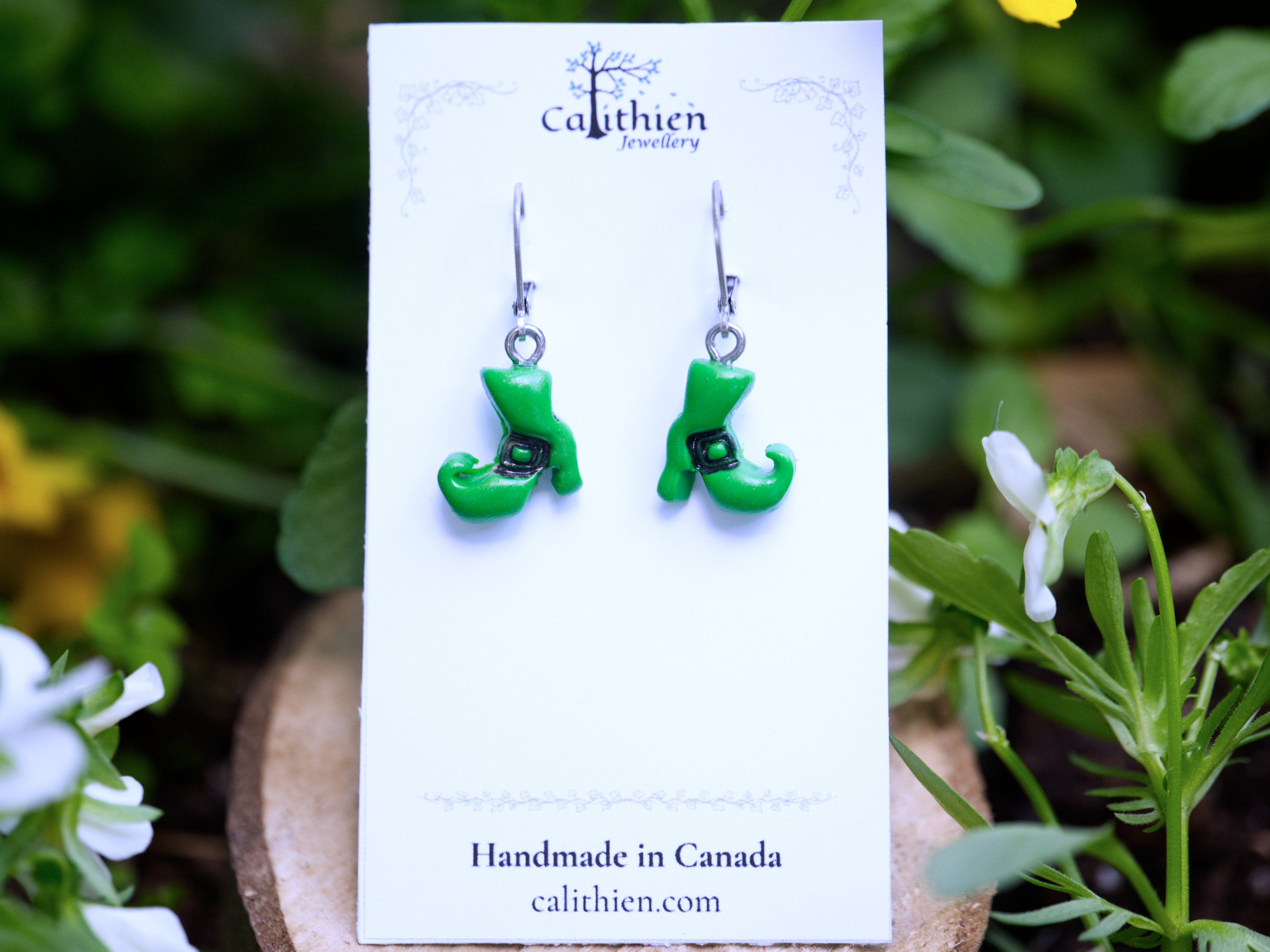 Green witch boot polymer clay earrings mounted on Calithien Jewellery branded display card reading Handmade in Canada