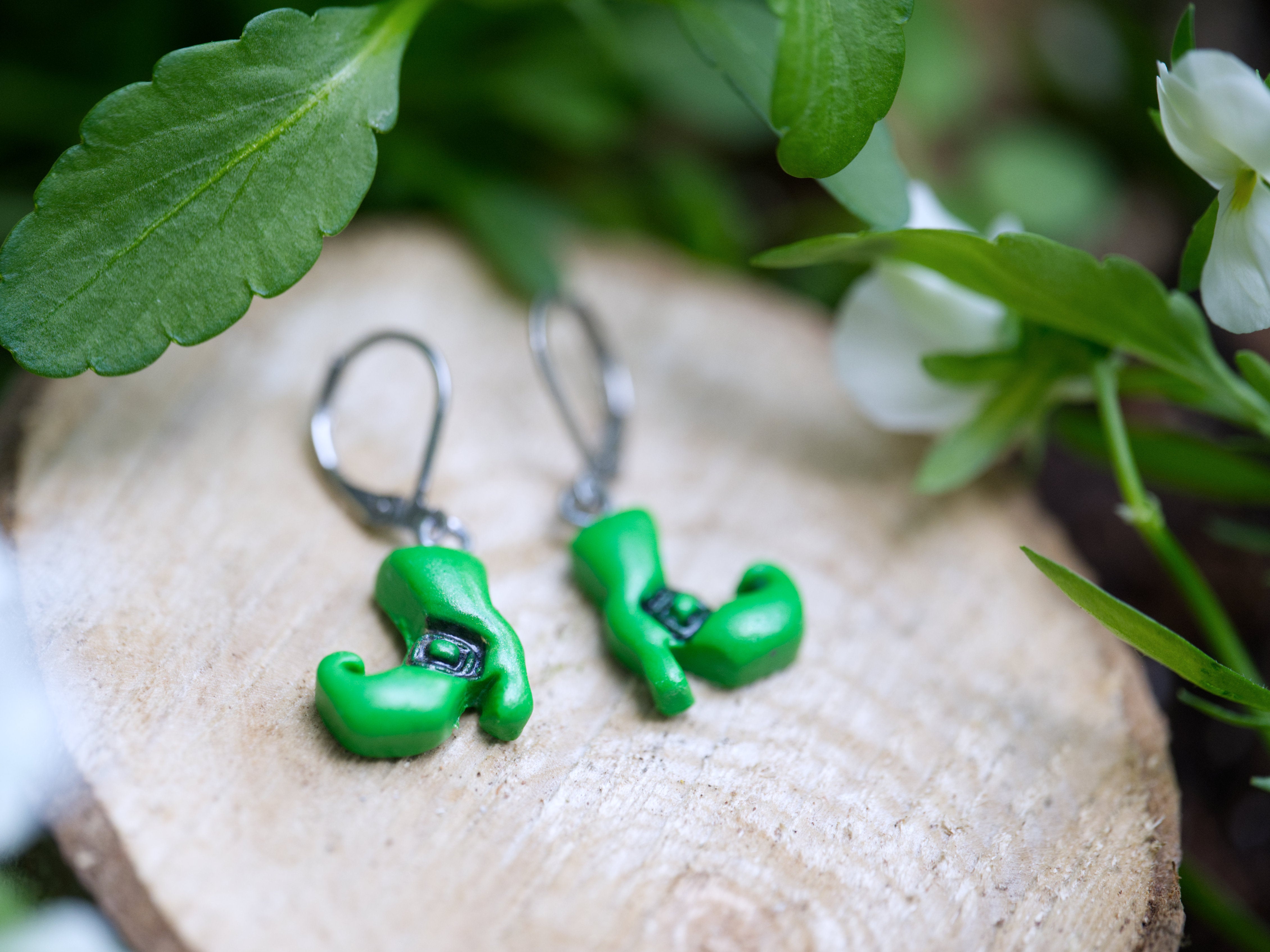 Close-up of green polymer clay witch boot earring charm showing hand-sculpted buckle detail and curled toe
