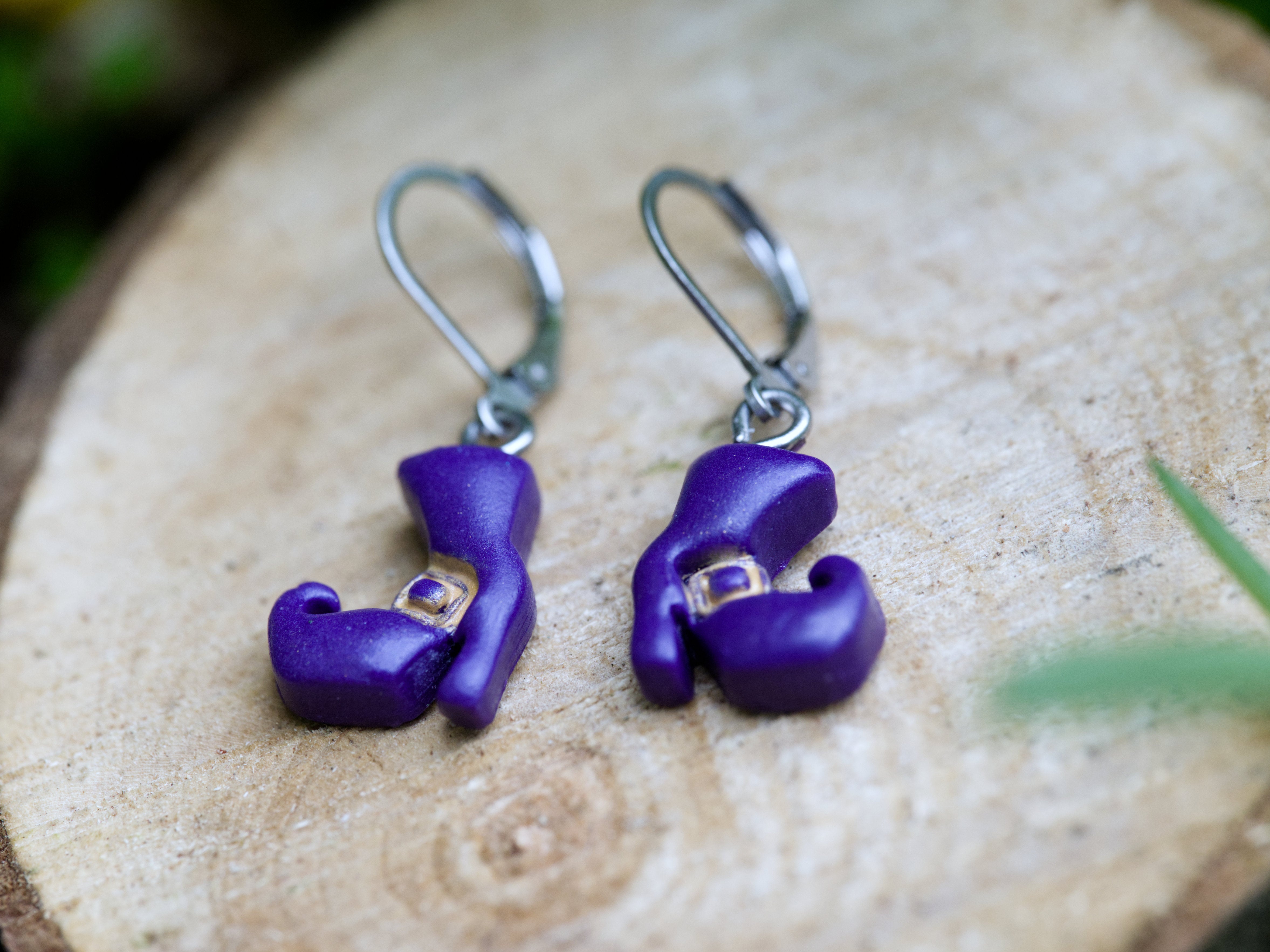 Close-up of purple polymer clay witch boot earring charm showing hand-sculpted buckle detail and curled toe