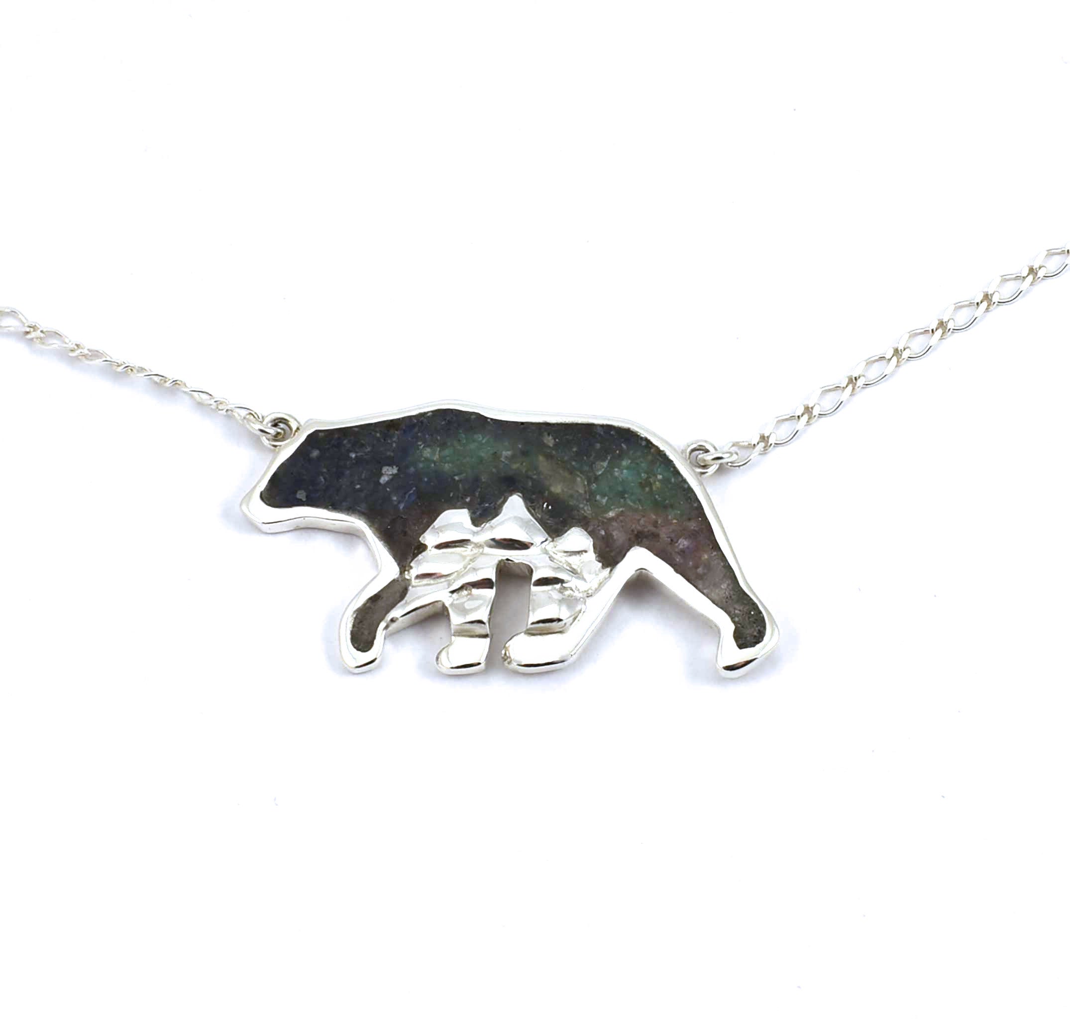 Front view of large sterling silver bear pendant with tree accents and crushed gemstone inlay
