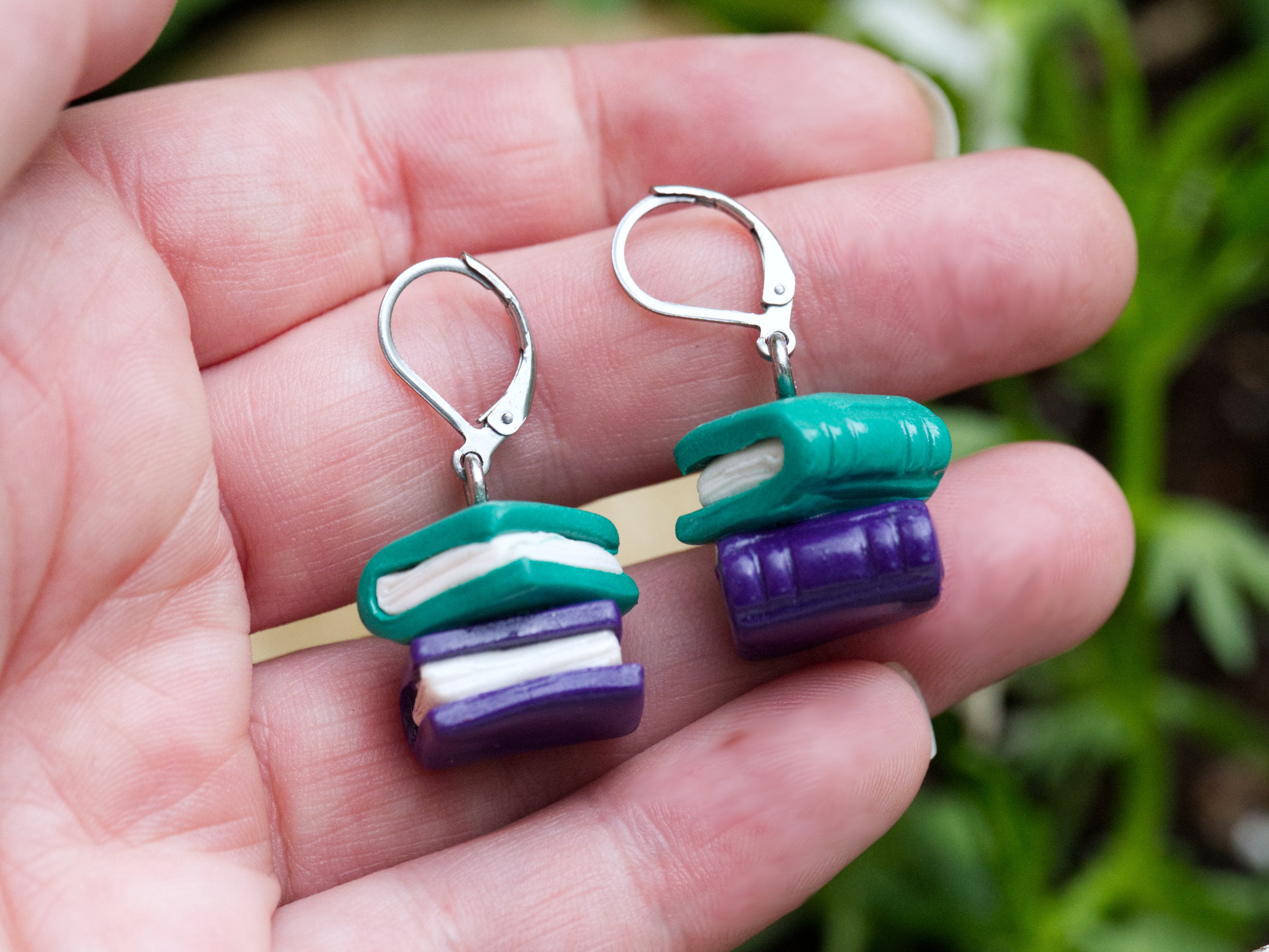 Teal and purple polymer clay book earrings shown at true scale approximately one centimetre square on Calithien Jewellery display card