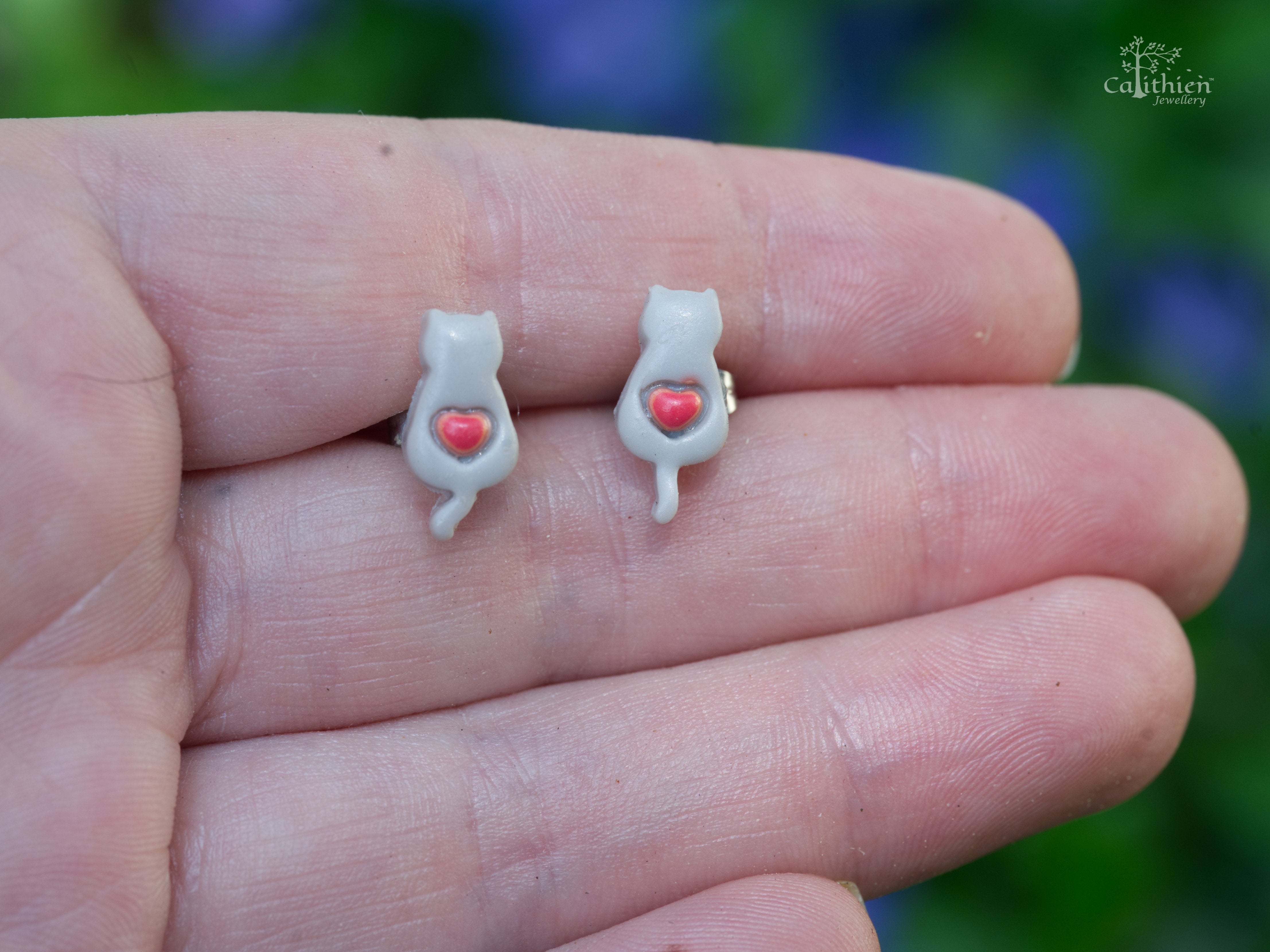 Pair of grey cat stud earrings on hand to display size