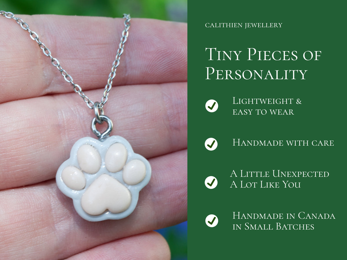Product information graphic highlighting features of the handmade grey paw print necklace and its stainless steel components.