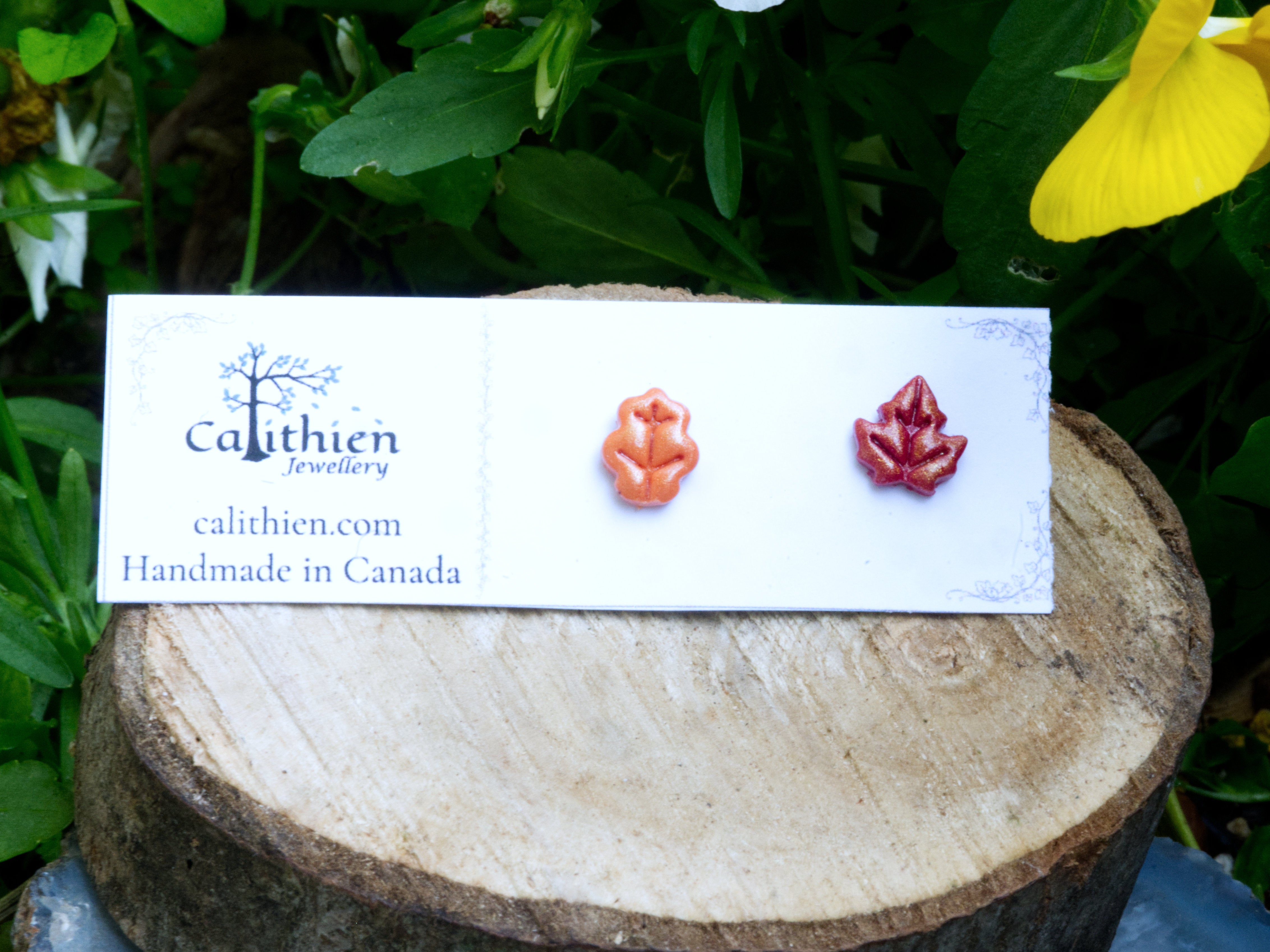 Mismatched oak and maple leaf stud earrings on Calithien Jewellery branded display card reading Handmade in Canada