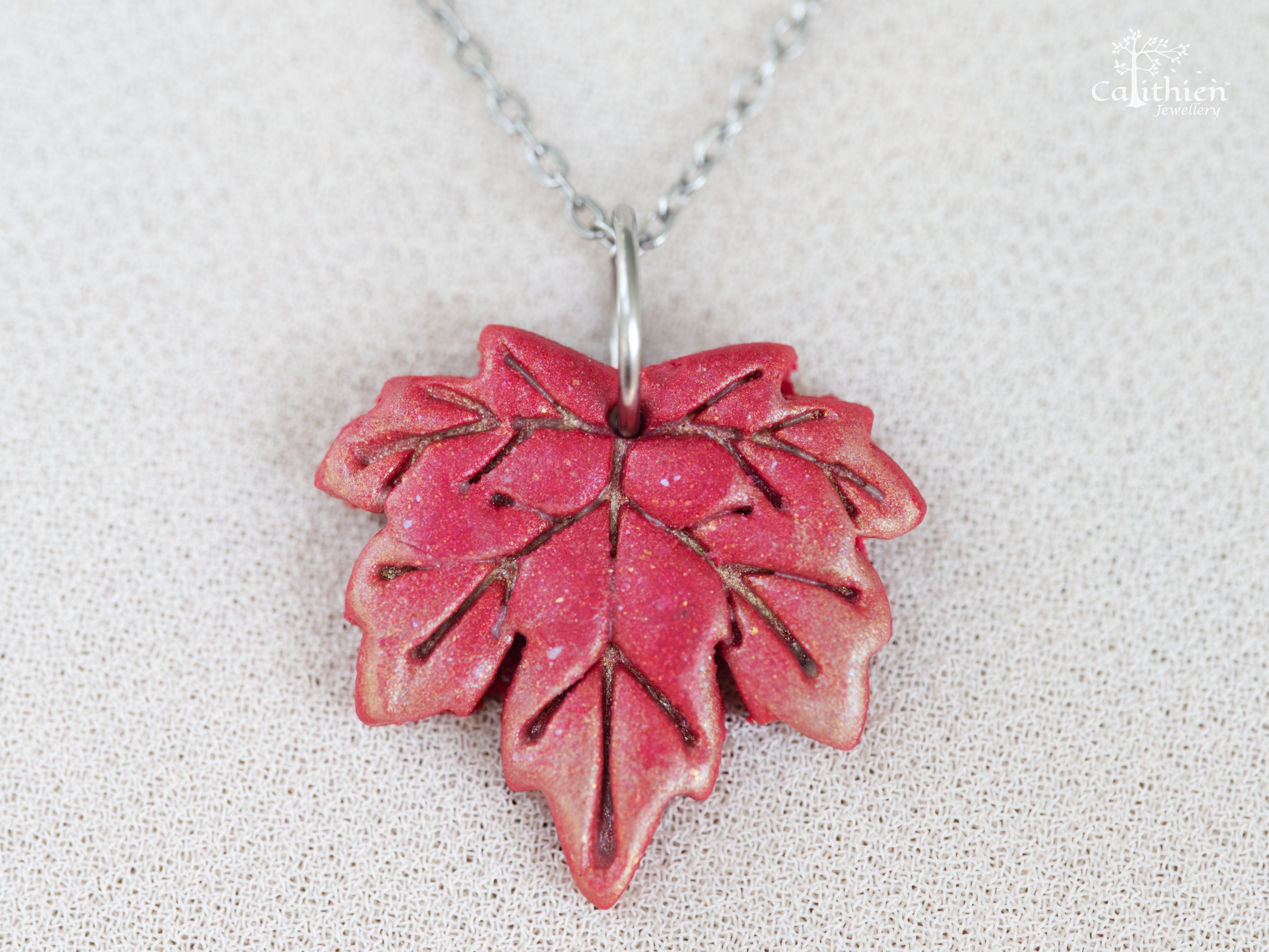  Close-up of red gold shimmer polymer clay maple leaf pendant showing hand-sculpted vein detail and warm light-catching shimmer finish