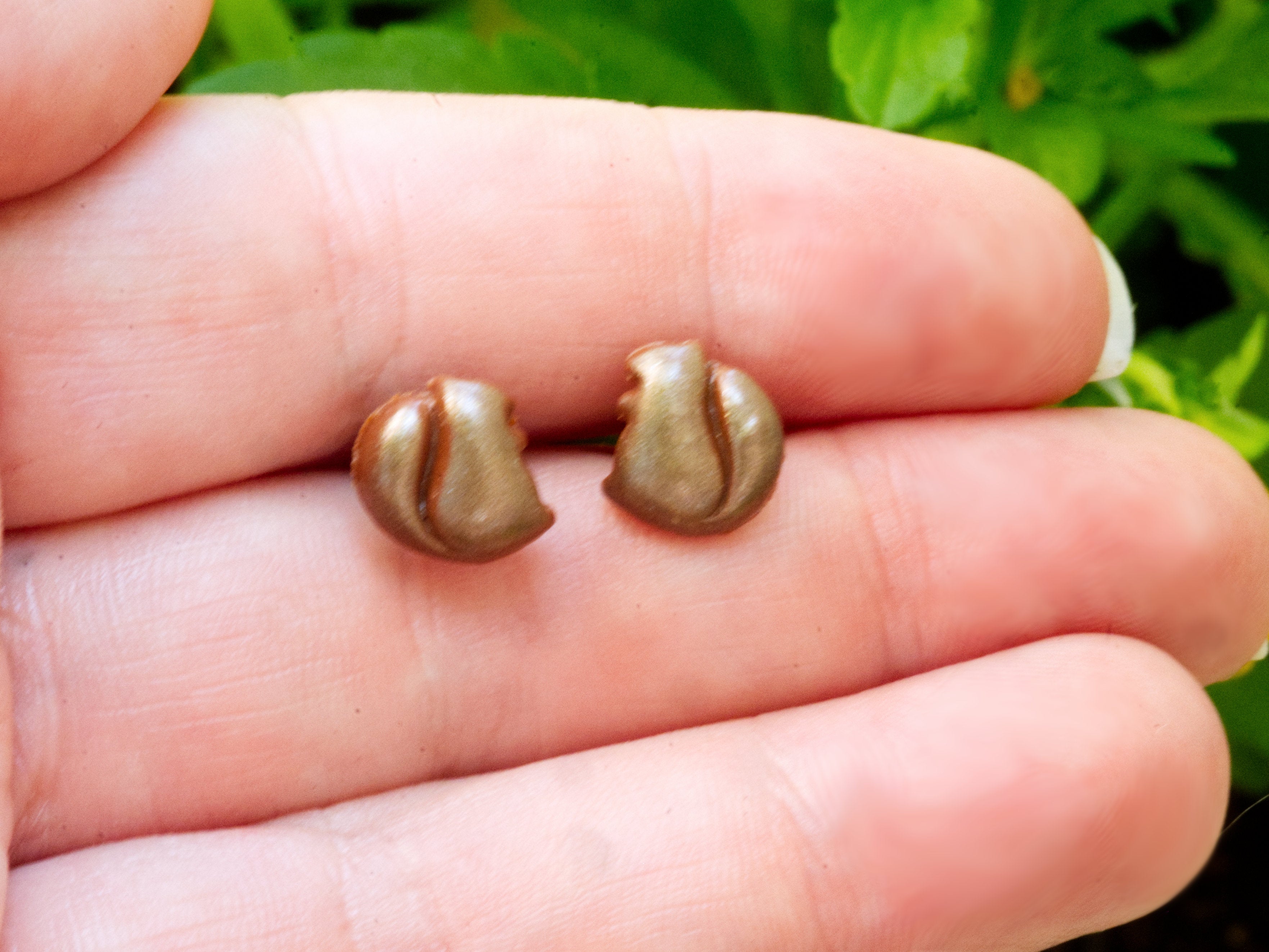 Brown polymer clay squirrel stud earrings on fingers to demonstrate size