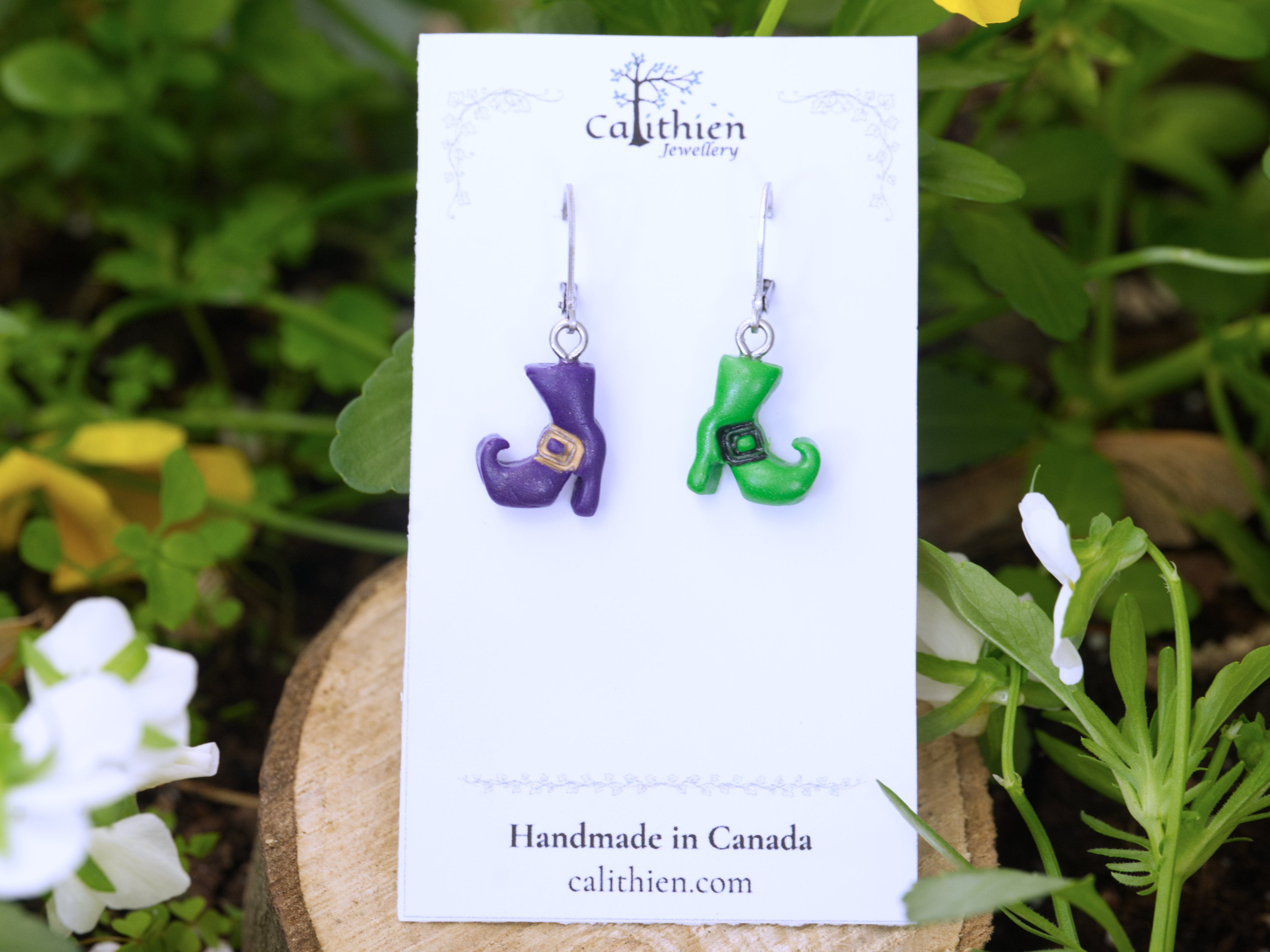 Mismatched witch boot earrings purple and green mounted on Calithien Jewellery branded display card reading Handmade in Canada