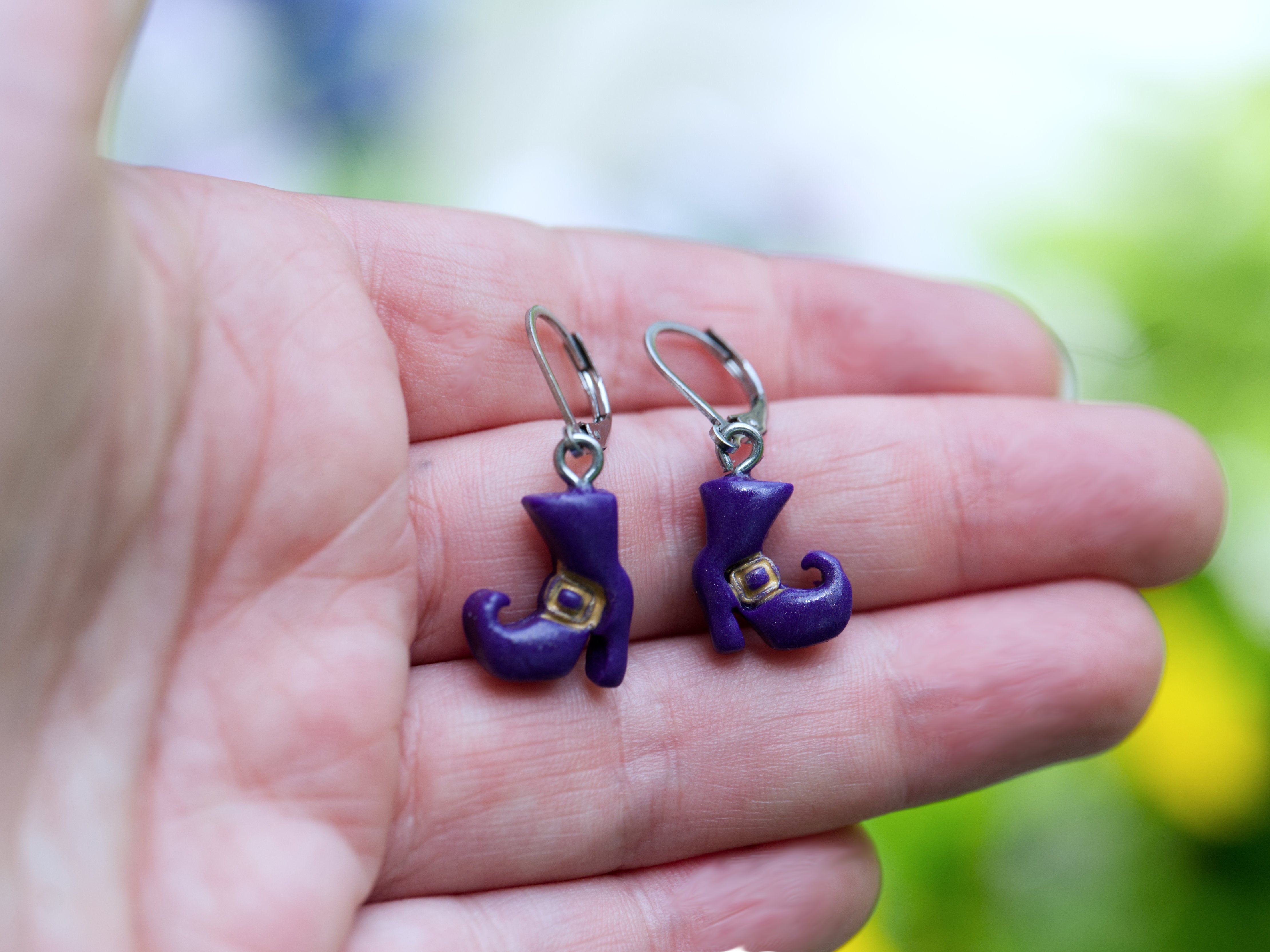 Purple polymer clay witch boot earring charm shown on hand to show scale
